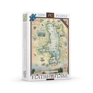 May include: A 1000-piece puzzle featuring a detailed map of Flathead Lake. The puzzle box displays the lake's outline, with illustrations of wildlife and landmarks. The text "Flathead Lake" is prominently displayed.