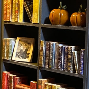 Two orange pumpkin decorations made by hand with polymer clay. A framed picture is also visible on one shelf.