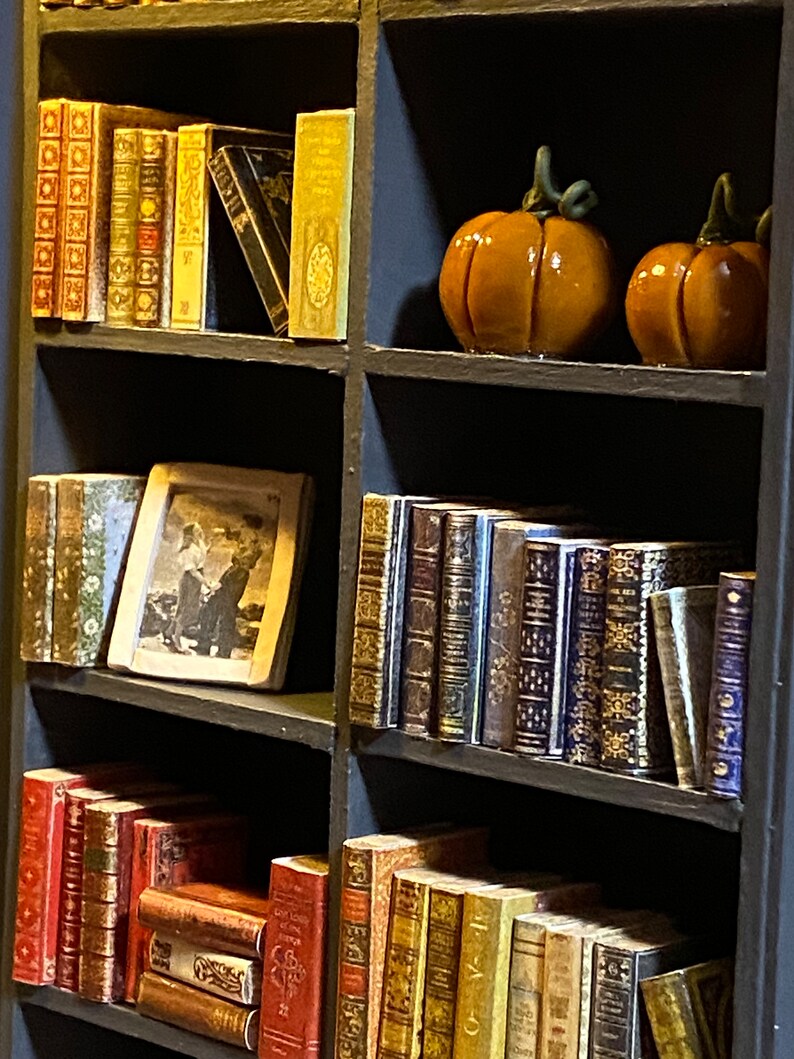 Two orange pumpkin decorations made by hand with polymer clay. A framed picture is also visible on one shelf.