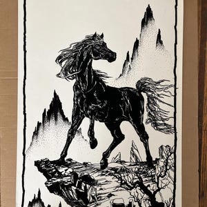 Peut inclure: Illustration en noir et blanc d'un cheval sur une falaise rocheuse, avec des montagnes en arrière-plan. Le cheval a une crinière et une queue fluides. L'œuvre est encadrée d'une bordure noire et comprend le texte "© 1973 AA SALES INC."