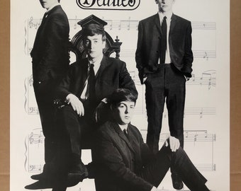 May include: Black and white photo of the Beatles band members. The band members are dressed in suits and are standing in front of a sheet of music. The word "Beatles" is written in a stylized font above the band members.