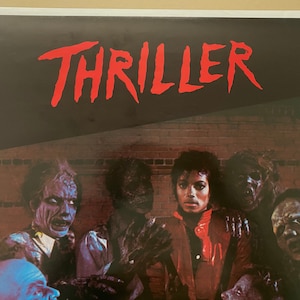 May include: A vintage poster for Michael Jackson's Thriller album. The poster features a red and black color scheme with the word "Thriller" in large red letters at the top. The poster also features a group of zombies surrounding Michael Jackson, who is wearing a red jacket.