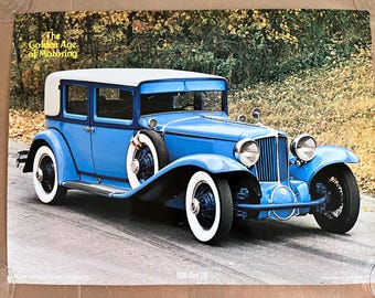 May include: A vintage blue 1930 Cord L-29 saloon with a white roof and chrome accents. The car is parked on a paved road with autumn foliage in the background. The text "The Golden Age of Motoring" is visible at the top of the image.