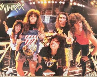 May include: A vintage concert poster featuring the heavy metal band Anthrax. The poster shows five band members in a concert setting with microphones, drums, and stage lights. The band's name is printed in large, bold letters at the top of the poster.