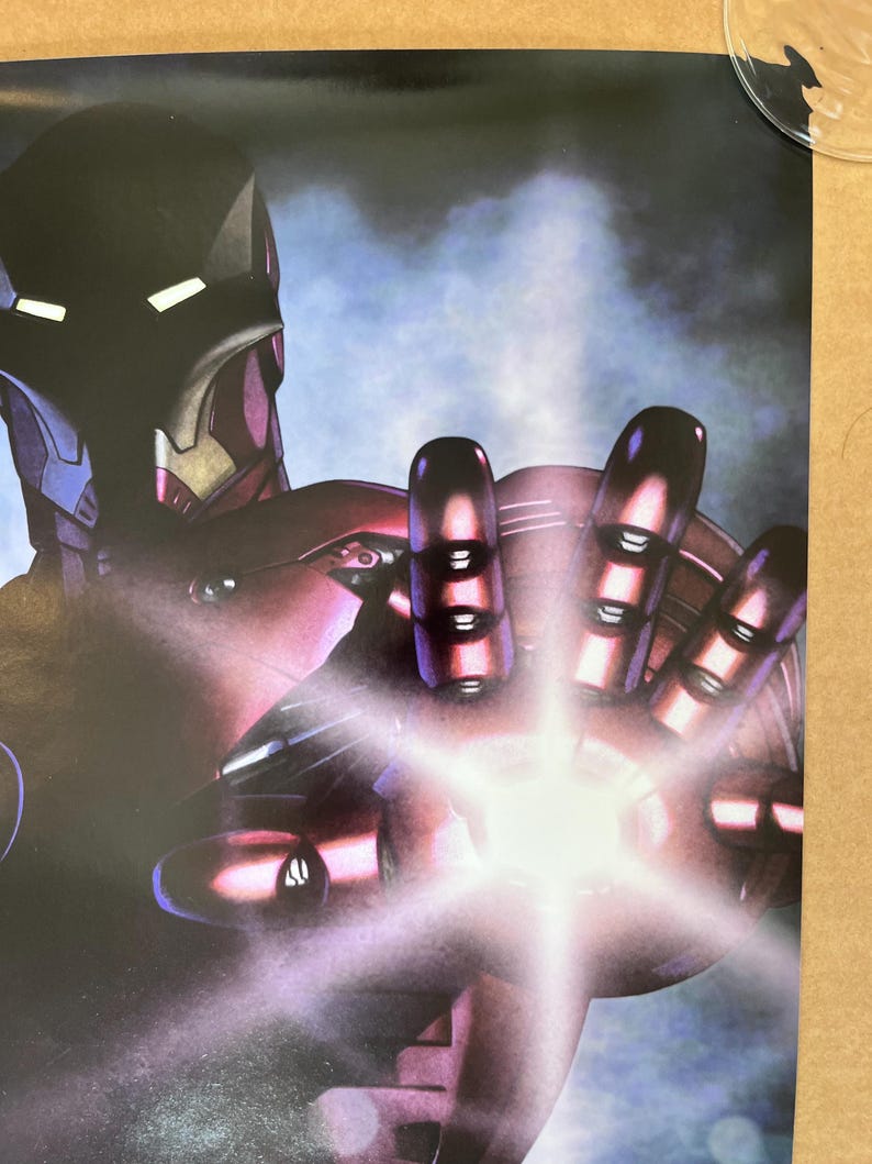 Op de afbeelding: Een close-up van een rood en zilveren Iron Man-figuur met een gloeiende repulsorstraal in zijn hand. Het figuur is geposeerd in een dynamische actiehoud, met zijn arm naar voren gestrekt. De achtergrond is wazig, blauw en paars.
