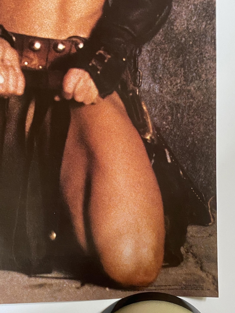 May include: A close-up of a person wearing a brown leather skirt and a black leather jacket. The person is kneeling on a sandy surface.