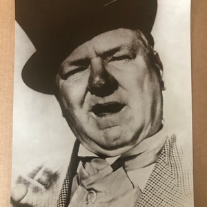 Peut inclure: Photographie en noir et blanc d'un homme portant un haut-de-forme et une veste de costume à motifs. Il regarde directement la caméra avec une expression sérieuse.