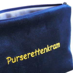 Könnte beinhalten: Eine dunkelblaue Samt-Tasche mit Reißverschluss und dem in Gelb gestickten Text "Purserettenkram".