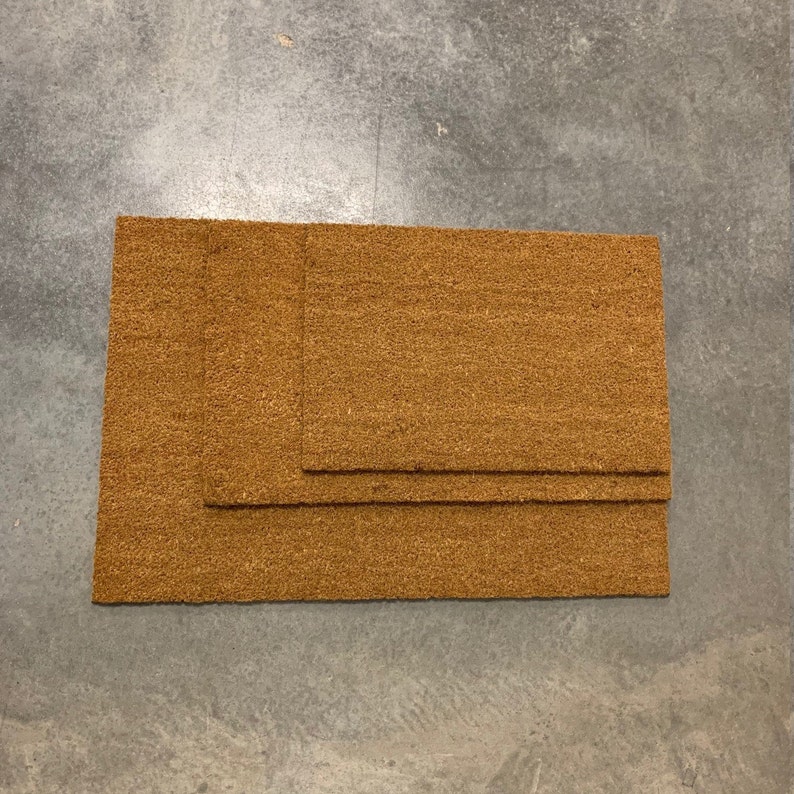 May include: Three brown coir doormats of different sizes stacked on top of each other.