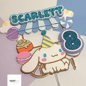 May include: A blue and white cake topper with the name "Scarlett" and the number "8" in blue glitter. The topper features a cartoon dog with a blue and yellow hat, a swirl of brown icing, a purple lollipop, and a blue and white striped awning.