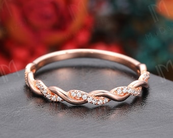 Puede incluir: Una delicada banda de oro rosa con un diseño trenzado y pequeños diamantes engastados en el metal.