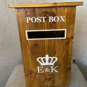 May include: A wooden post box with a white "POST BOX" sign, a white crown, and the initials "E & K" on the front.
