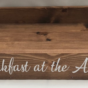 May include: A wooden serving tray with black accents and the text "Breakfast at the Alders" in white lettering.