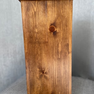 May include: A wooden box with a dark brown stain. The box is made of solid wood with a visible grain pattern.