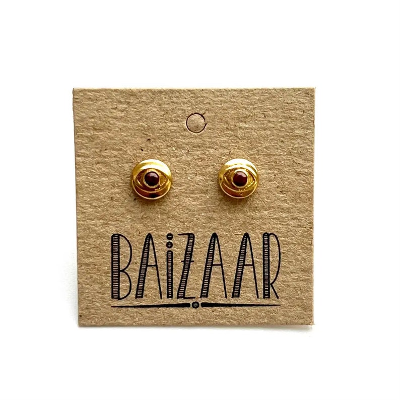 Decorated evil eye stud earrings with faceted ruby in sterling silver or brass.