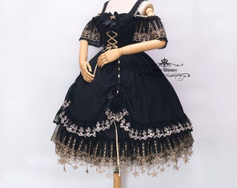 May include: A black Lolita dress with gold detailing. The dress has a square neckline, off-the-shoulder sleeves, and a corset-style bodice. The skirt is layered, with gold lace trim and star-shaped embellishments. A black bow is on the bodice.