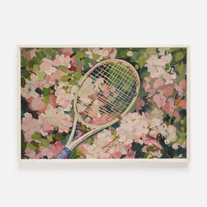 May include: A white tennis racket with pink and green accents is lying on a bed of pink flowers. The racket is partially obscured by the flowers, creating a visually interesting composition.