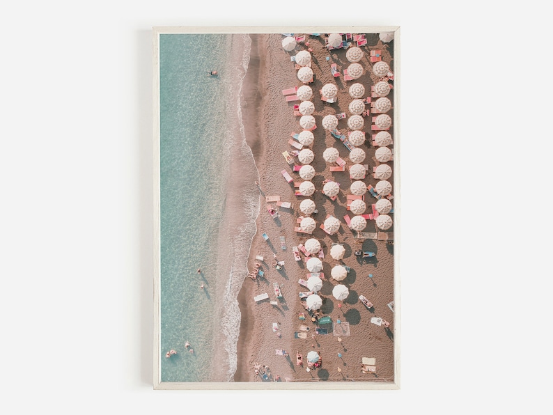 Peut inclure: Vue a&eacute;rienne d'une plage de sable avec une eau turquoise et des rang&eacute;es de parasols blancs. Les parasols sont align&eacute;s en ligne droite le long du rivage, avec des personnes assises en dessous.