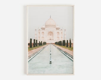 May include: A white marble building with a large dome and minarets, reflected in a pool of water. The building is surrounded by a symmetrical row of green trees.