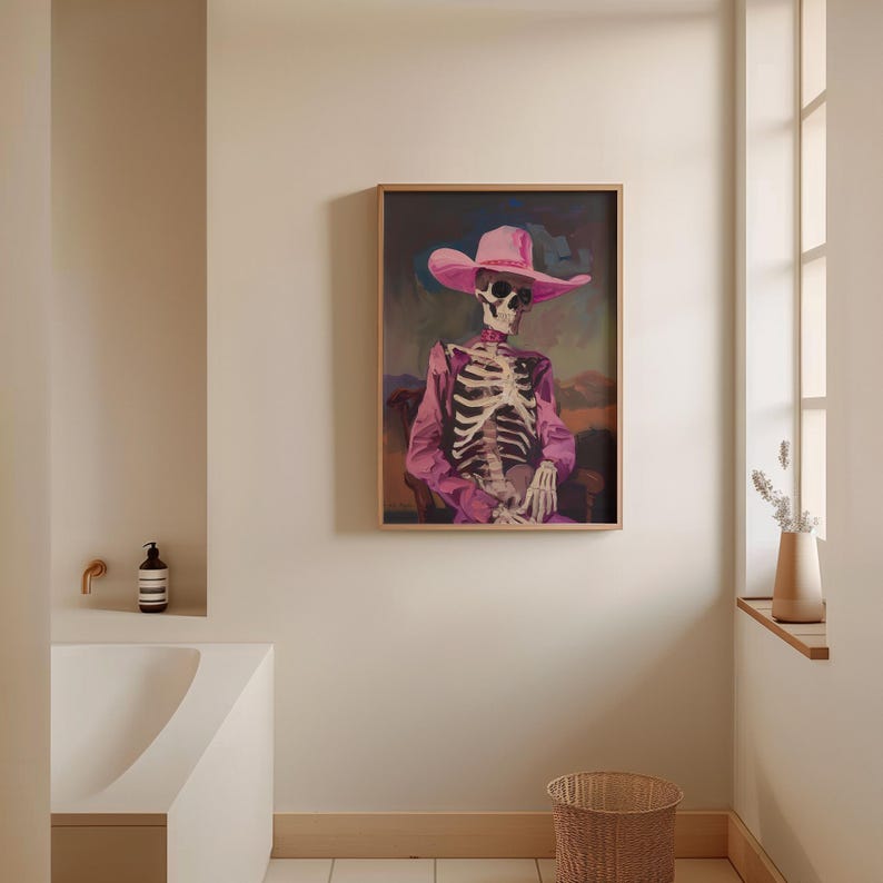 May include: A framed painting of a skeleton wearing a pink cowboy hat and a pink shirt. The skeleton is sitting in a chair with its hands resting on its lap. The background is a blurry landscape.