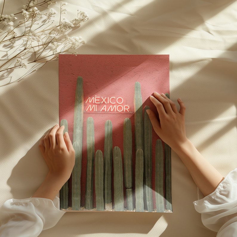 May include: A pink poster with a neon sign that reads "M&Eacute;XICO MI AMOR" in white letters. The poster features a row of green cactus plants against a pink background.