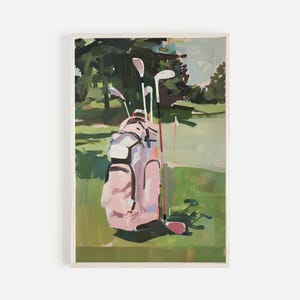 May include: A painting depicting a golf course with a pink golf bag and clubs on a green fairway. The background shows trees and a flag, creating a tranquil outdoor scene. The artwork is framed.