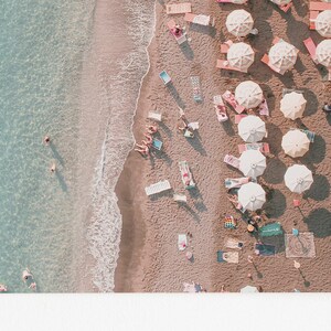 Peut inclure: Vue a&eacute;rienne d'une plage de sable avec une eau turquoise. Des gens nagent et prennent le soleil sous des parasols et des chaises longues color&eacute;s.