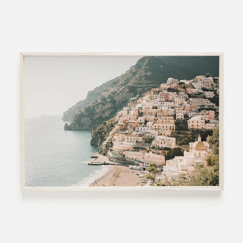 May include: A panoramic view of a coastal town built into a hillside, with colorful buildings and a white church with a dome. The town is situated on a rocky cliff overlooking a blue ocean.