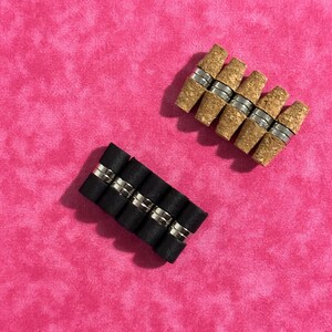 May include: Two sets of magnetic bottle stoppers. One set is black and the other is brown. Both sets are arranged in a row.
