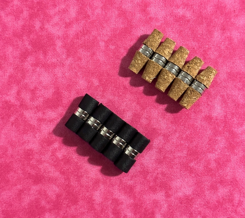 May include: Two sets of magnetic bottle stoppers. One set is black and the other is brown. Both sets are arranged in a row.