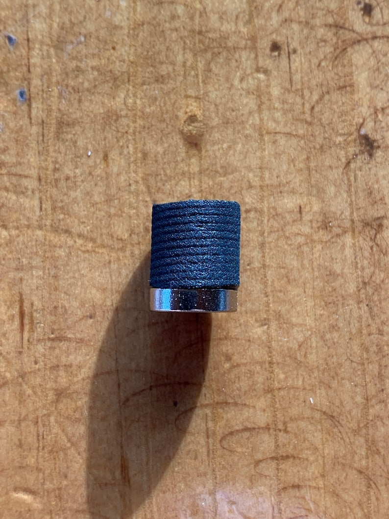 May include: A black and silver knob with a textured surface.