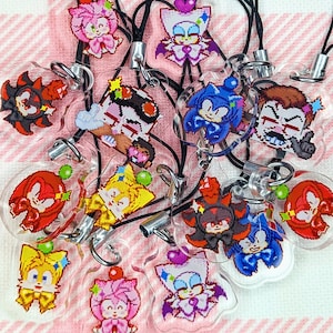 May include: A collection of 12 colourful character charms on clear plastic keychains. The characters are from the Sonic the Hedgehog video game series. The charms feature characters like Sonic, Tails, Knuckles, Shadow, Amy, and Rouge.
