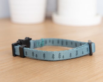 May include: A light blue dog collar with a black buckle and a repeating pattern of small green trees.