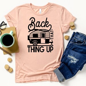 May include: A pink t-shirt with a black graphic of a camper van and the text "Back that thing up."
