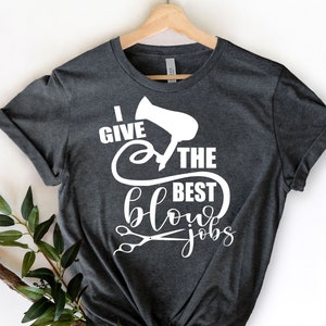 Może przedstawiać: Szary t-shirt z białym napisem "Daję najlepsze suszenia" z grafiką suszarki do włos&oacute;w i nożyczek.