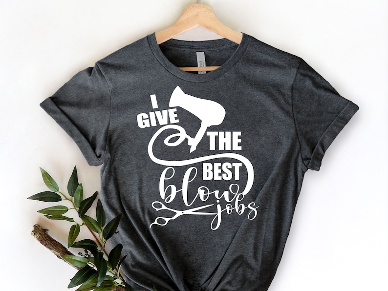 Może przedstawiać: Szary t-shirt z białym napisem "Daję najlepsze suszenia" z grafiką suszarki do włos&oacute;w i nożyczek.