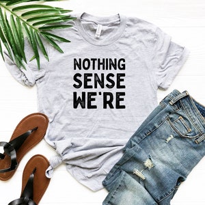 May include: A gray t-shirt with the text "NOTHING SENSE WE'RE" printed in black.
