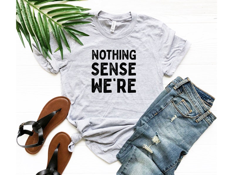 May include: A gray t-shirt with the text "NOTHING SENSE WE'RE" printed in black.