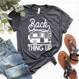 May include: A dark gray t-shirt with a white graphic of a camper and the text "Back that thing up".