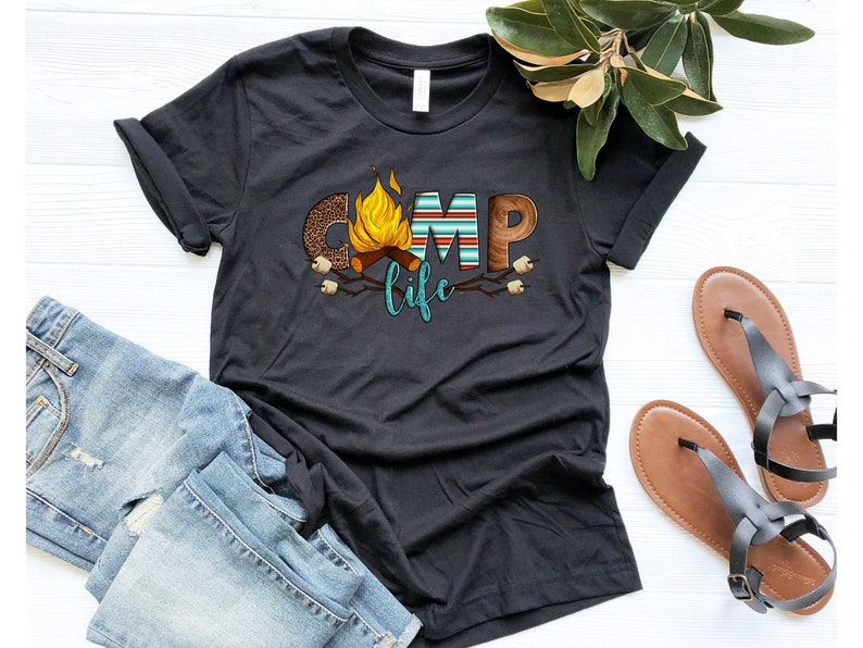 May include: Black t-shirt featuring a graphic design of the word "camp" with a campfire and the words "life" underneath.