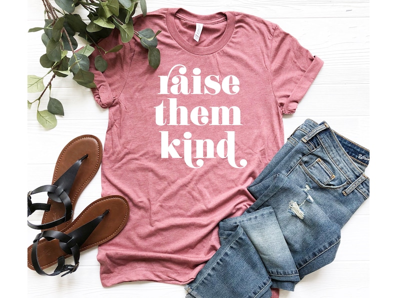 May include: A pink t-shirt with the text "raise them kind" in white lettering.