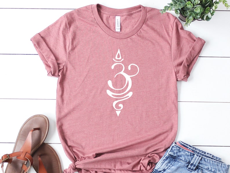 May include: A mauve colored t-shirt with a white Om symbol graphic. The shirt is made of a soft, comfortable material.