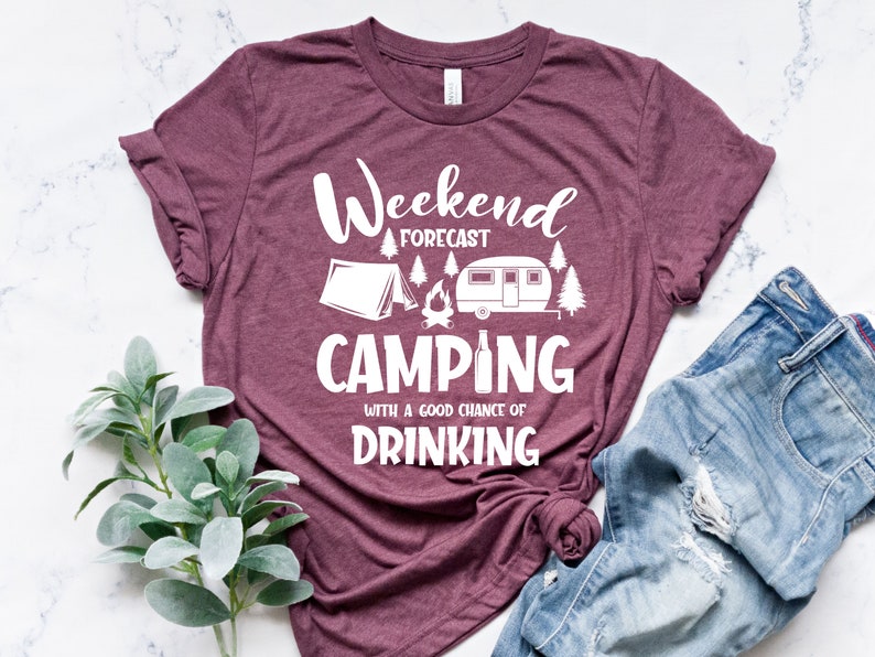 May include: A maroon t-shirt with white text that reads "Weekend Forecast Camping with a good chance of drinking". The shirt features a white silhouette of a tent, campfire, camper, and beer bottle.