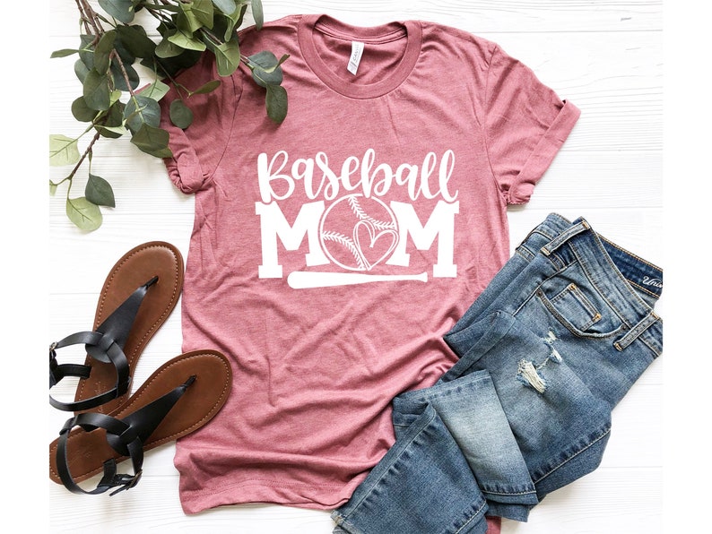 Op de afbeelding: Een roze T-shirt met de tekst "Baseball Mom" in wit, met een baseball- en hartgrafiek.