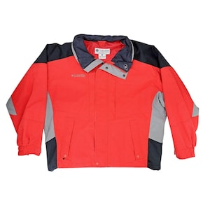 May include: A red Columbia jacket with black and gray accents. The jacket has a collared neckline, a zipper closure, and two front pockets. The Columbia logo is visible on the chest. The jacket is designed for outdoor activities.