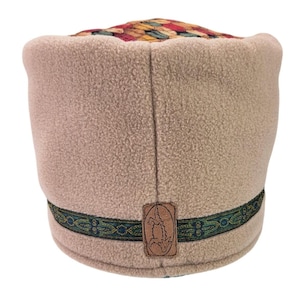 May include: A beige fleece hat with a flat top featuring a multi-colored woven pattern in shades of red, green, and gold. A dark green and gold decorative ribbon encircles the base, accented by a rectangular brown leather patch with an alligator.