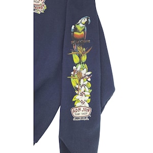 May include: Navy blue sweatshirt with a colorful parrot and floral design on the sleeve. The sleeve also features the text "RON JON SURF SHOP" in a circular logo. The sweatshirt has a crew neck and long sleeves.