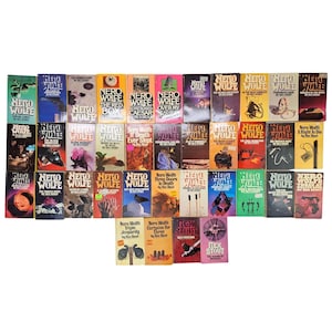 May include: A collection of vintage Nero Wolfe mystery novels by Rex Stout. The books feature colorful covers with various designs and titles, arranged in a grid. The spines display the author's name and the series title.
