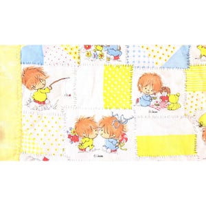 Puede incluir: Un edredón de retazos con ilustraciones de dibujos animados de niños en varias escenas. El edredón tiene un esquema de color amarillo, blanco y azul con patrones de puntos y florales. Las ilustraciones representan a niños pescando, haciendo picnic y abrazándose.