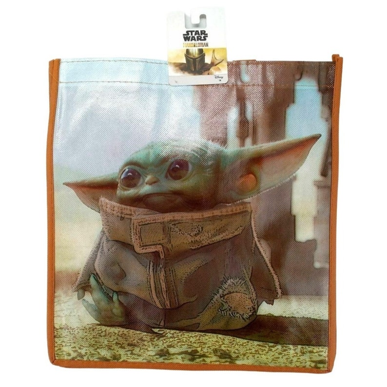 Op de afbeelding: Een herbruikbare boodschappentas met een kleurrijk beeld van "The Child" uit de Star Wars-serie "The Mandalorian". De tas is gemaakt van geweven stof met een bruine rand.